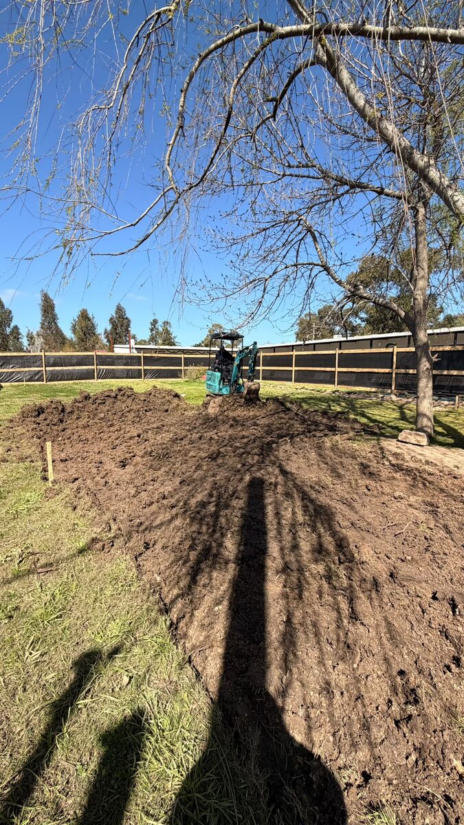 Miniexcavadora haciendo movimiento de suelos en un jardín de Maldonado